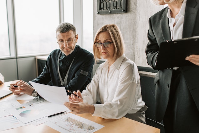 three real estate experts looking over documents with a clients earnings)